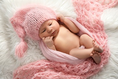 Photo of Cute newborn baby in hat lying on fuzzy blanket, top view
