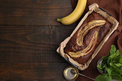 Photo of Delicious banana bread and ingredients on wooden table, flat lay. Space for text