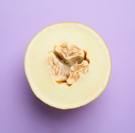 Photo of Half of ripe tasty melon on violet background, top view