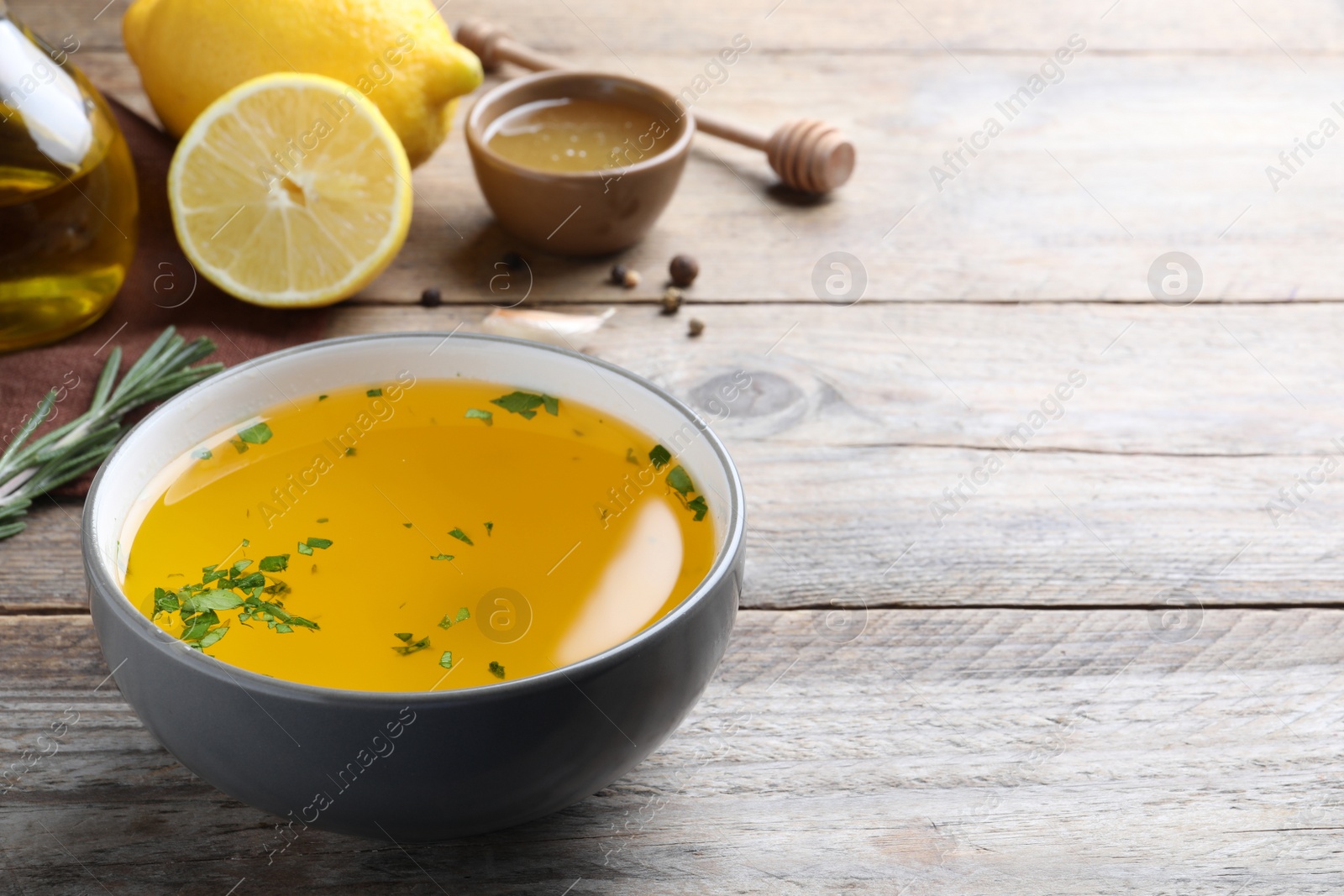 Photo of Bowl with lemon sauce and ingredients on wooden table, space for text. Delicious salad dressing