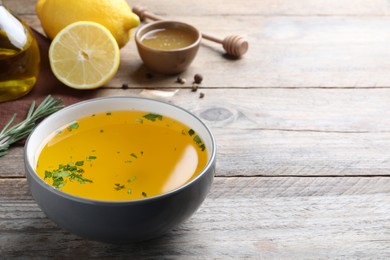 Bowl with lemon sauce and ingredients on wooden table, space for text. Delicious salad dressing