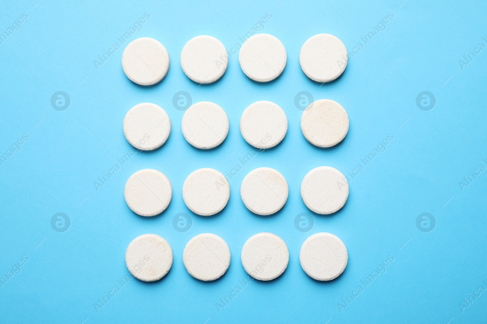 Photo of White pills on light blue background, flat lay