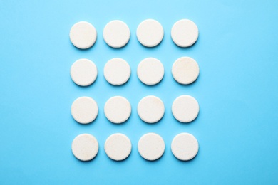 Photo of White pills on light blue background, flat lay