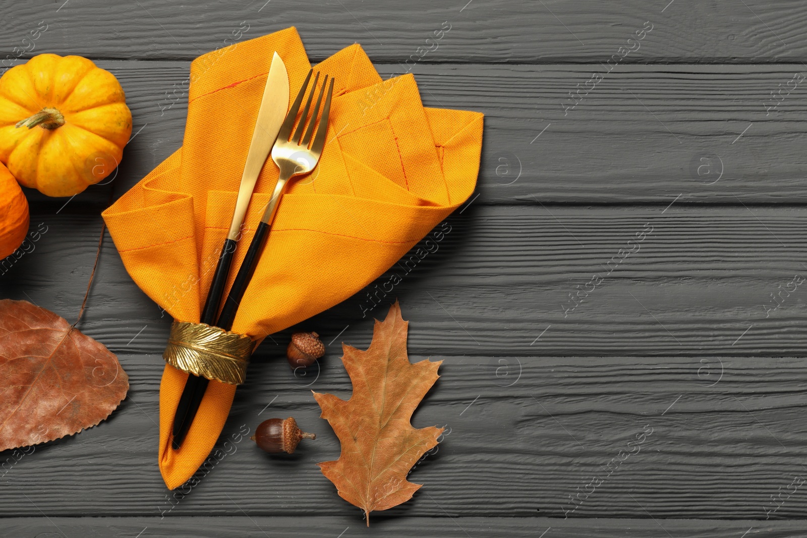 Photo of Cutlery, napkin and autumn decoration on gray wooden background, flat lay with space for text. Table setting