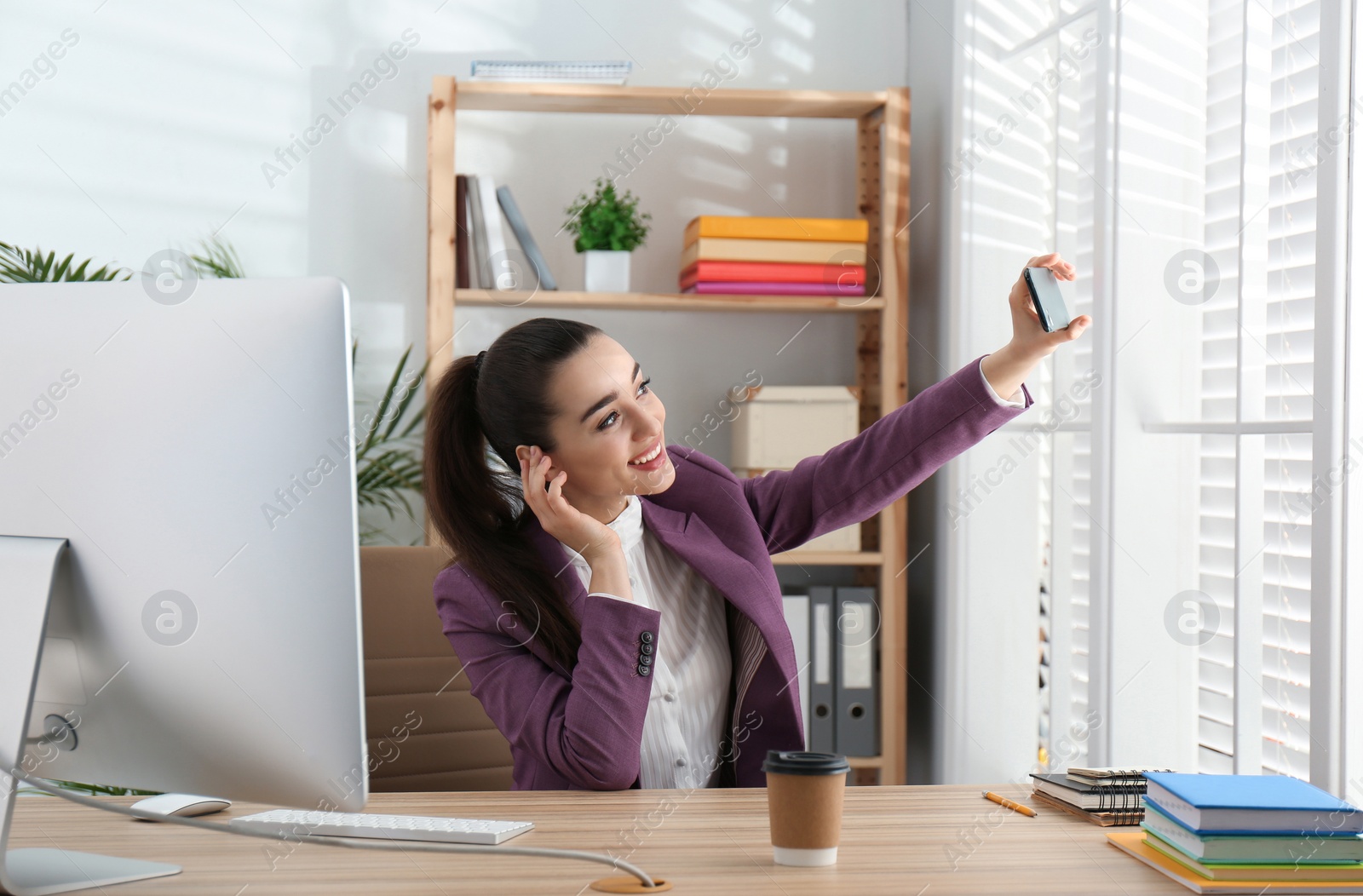 Photo of Lazy employee taking selfie at table in office