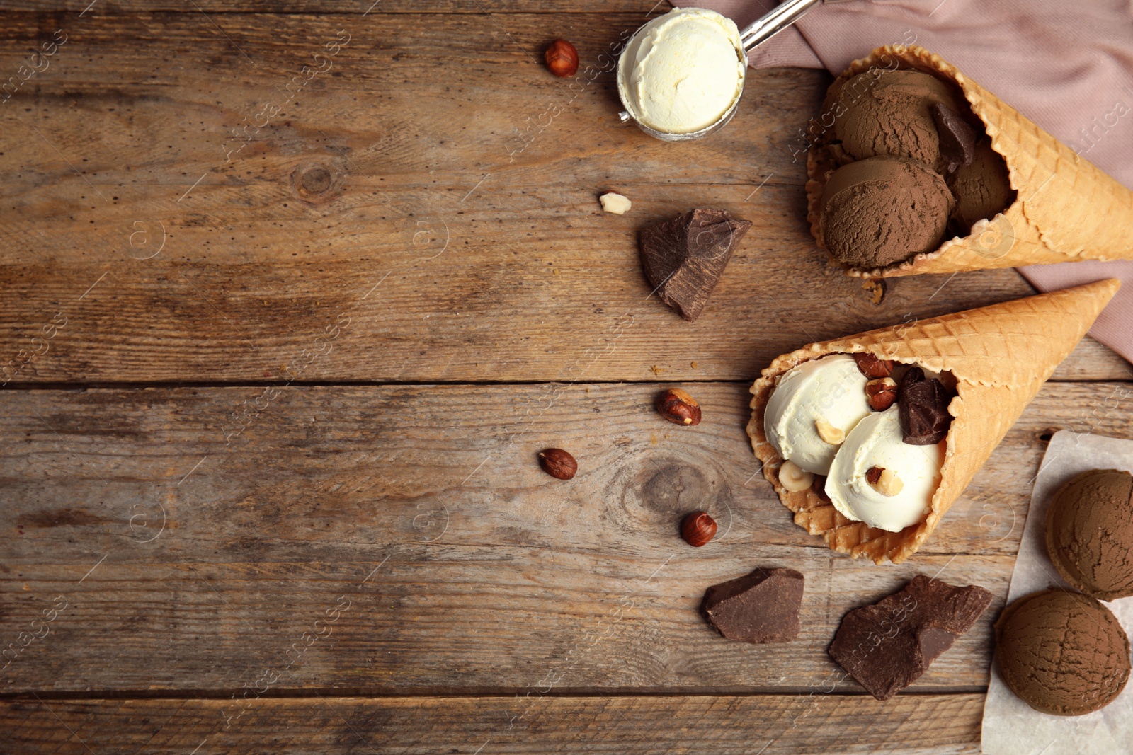 Photo of Flat lay composition with delicious ice creams in waffle cones on wooden table, space for text