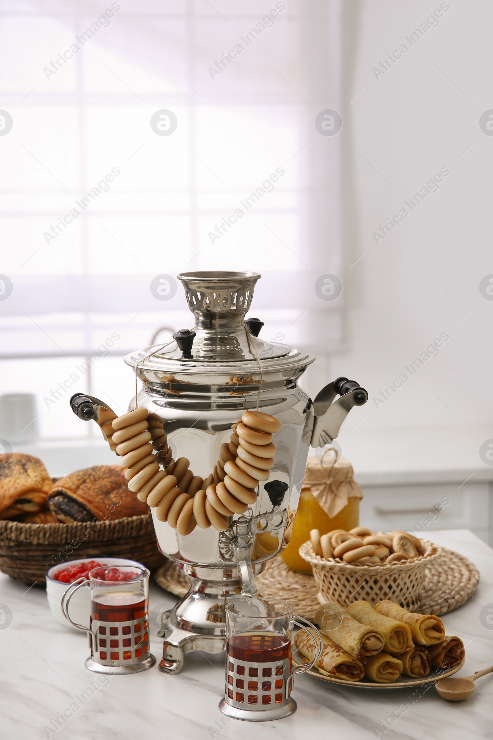 Photo of Traditional Russian samovar with treats on white table at home