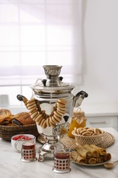 Traditional Russian samovar with treats on white table at home