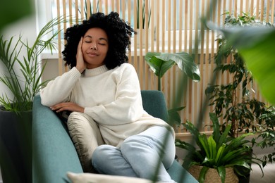 Woman relaxing on sofa near beautiful houseplants at home