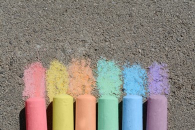 Photo of Colorful chalk sticks on asphalt outdoors, flat lay. Space for text