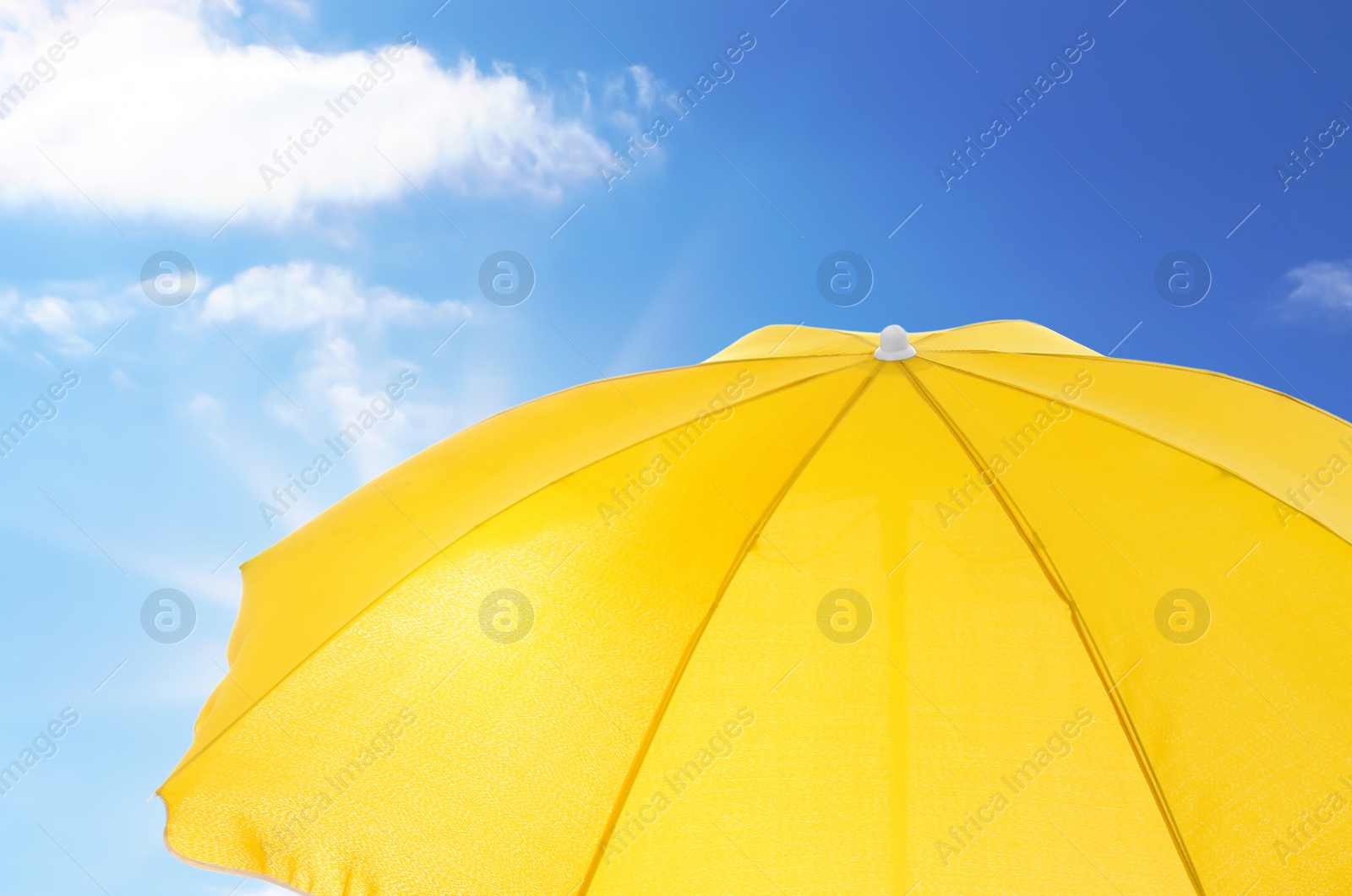 Image of Open big yellow beach umbrella and beautiful blue sky with white clouds on background