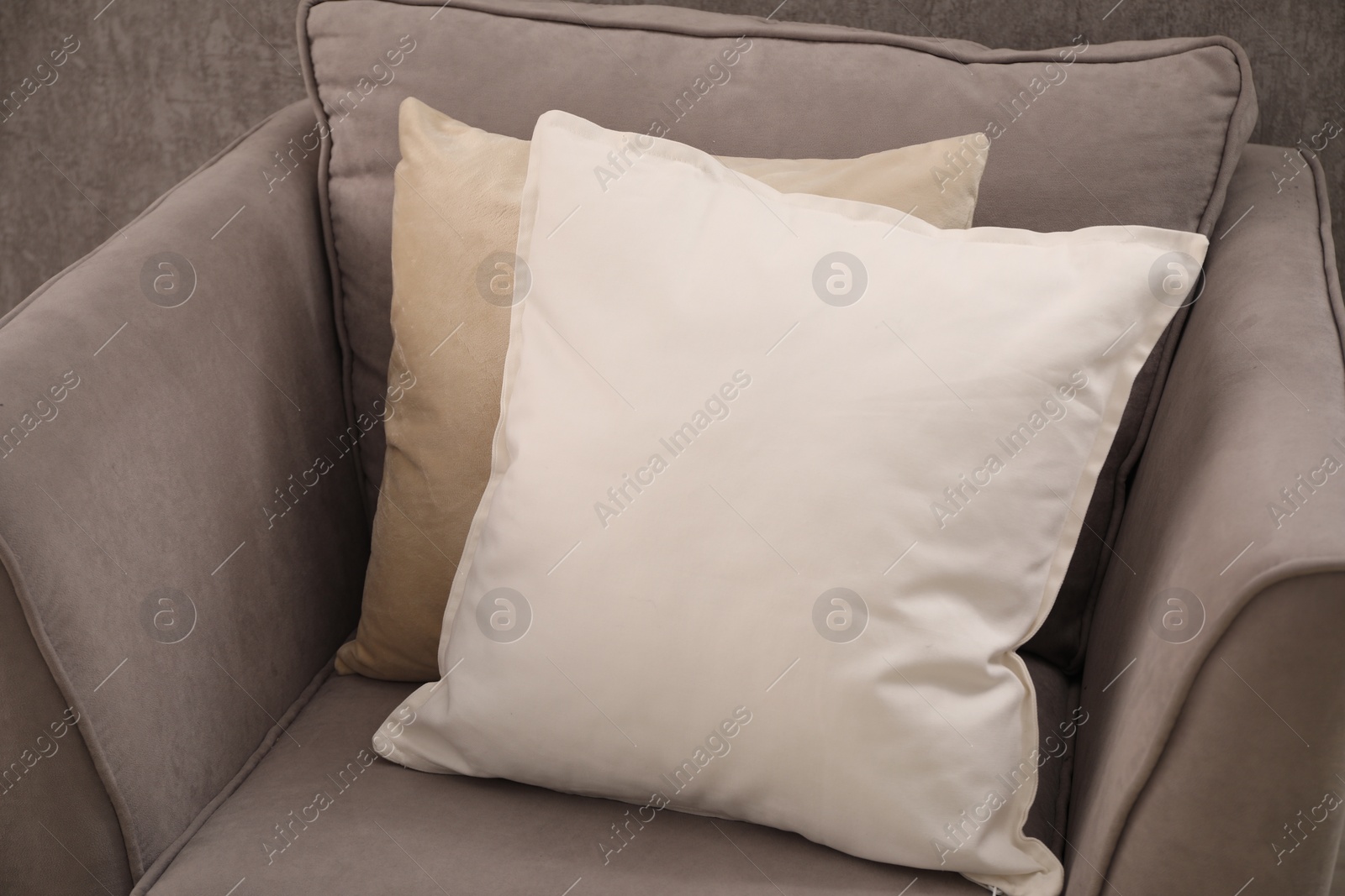 Photo of Soft pillows on grey armchair in room