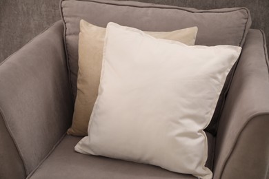 Soft pillows on grey armchair in room