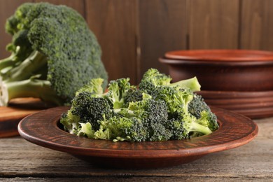 Photo of Plate with fresh raw broccoli on wooden table, closeup