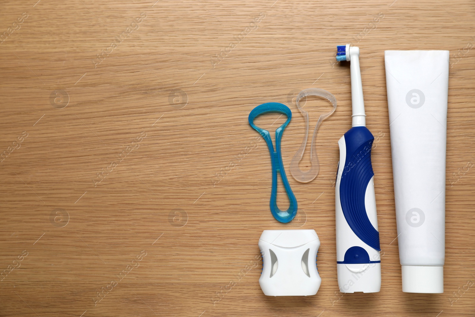 Photo of Flat lay composition with tongue cleaners and teeth care products on wooden table, space for text