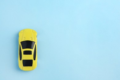 Photo of One yellow car on light blue background, top view with space for text. Children`s toy