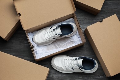 Photo of Sneakers and cardboard shoe boxes on wooden floor, flat lay