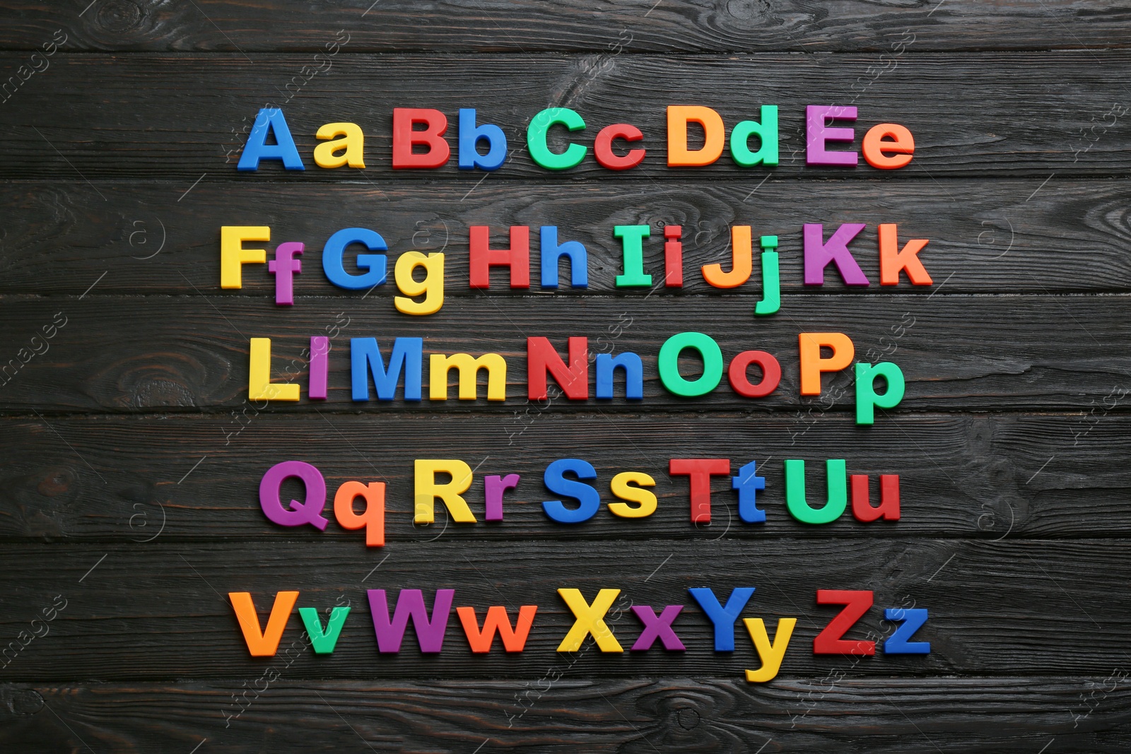 Photo of Colorful magnetic letters on black wooden background, flat lay. Alphabetical order