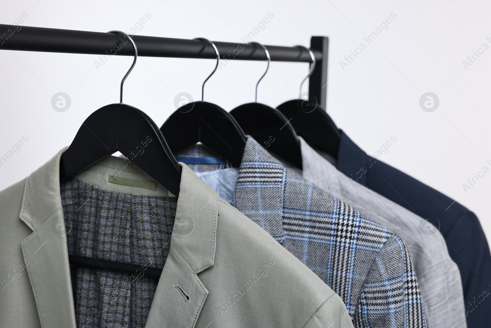 Photo of Dry-cleaning service. Many different clothes hanging on rack against white background, closeup