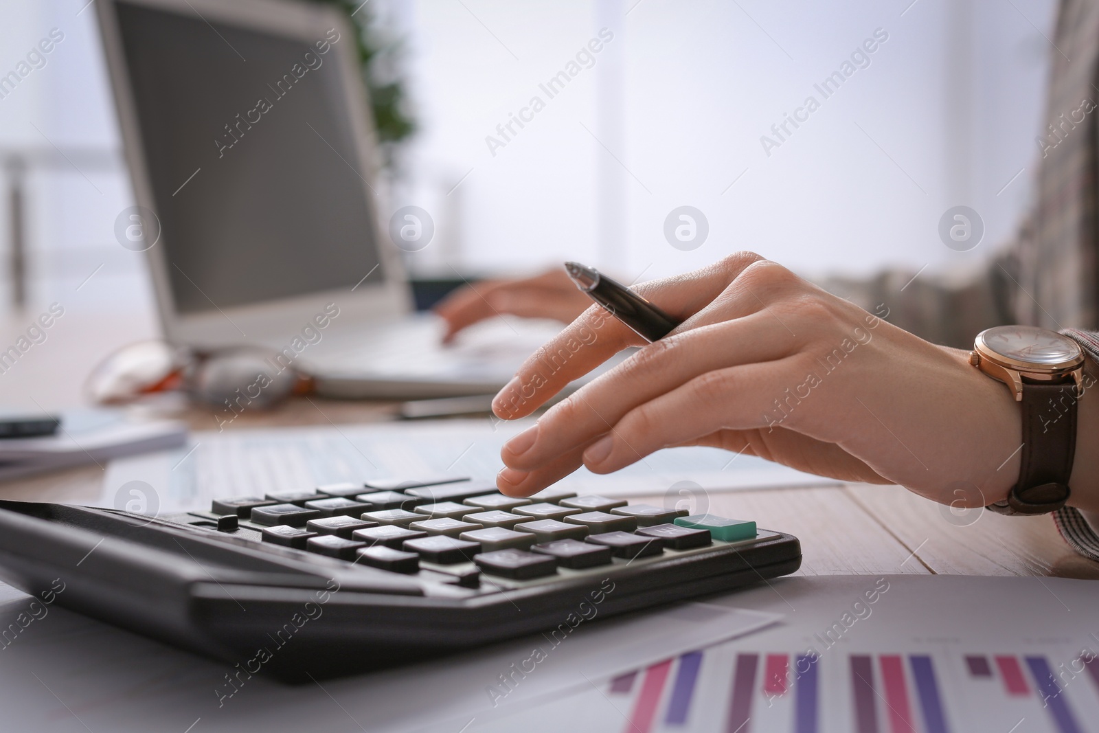 Photo of Tax accountant with calculator working at table in office, closeup