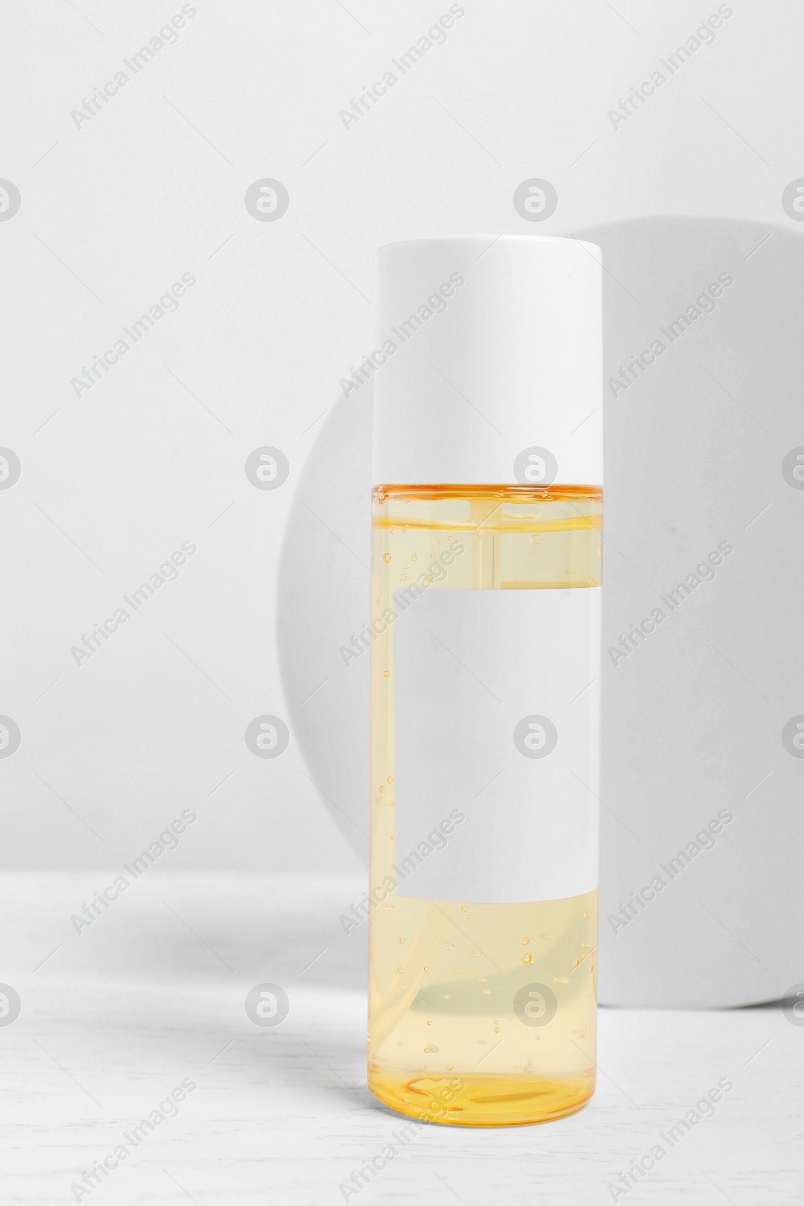 Photo of Bottle of cosmetic product on white wooden table