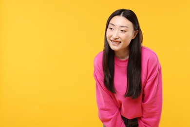 Photo of Portrait of smiling woman on orange background. Space for text