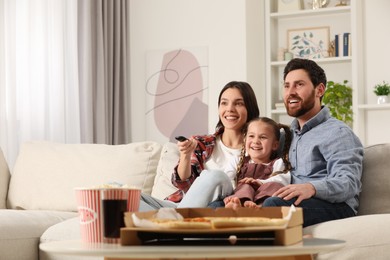 Photo of Happy family watching TV with popcorn and pizza on sofa at home