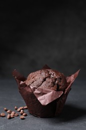 Photo of Tasty chocolate muffin on black textured table, closeup. Space for text