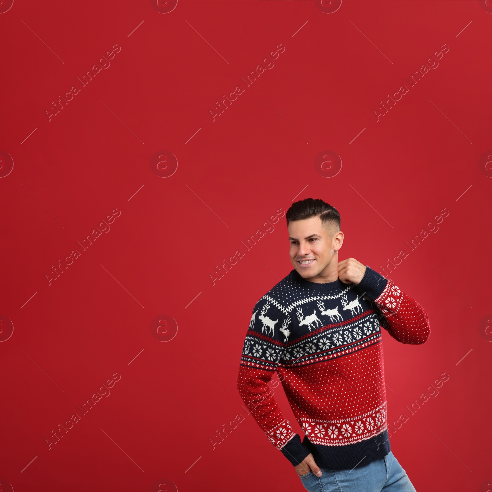 Photo of Handsome man in Christmas sweater on red background, space for text