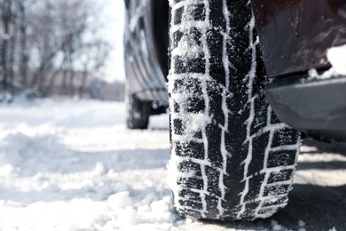 Photo of Car with winter tires on snowy road, closeup view. Space for text