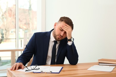 Photo of Man suffering from migraine at workplace in office