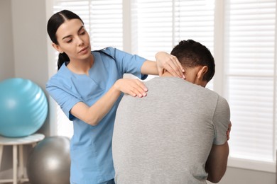 Photo of Orthopedist examining man's neck in clinic. Scoliosis treatment