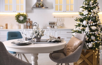 Photo of Table with set of dishware and beautiful Christmas decor in kitchen interior