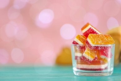 Photo of Delicious jelly candies in bowl on table against blurred background, closeup. Space for text