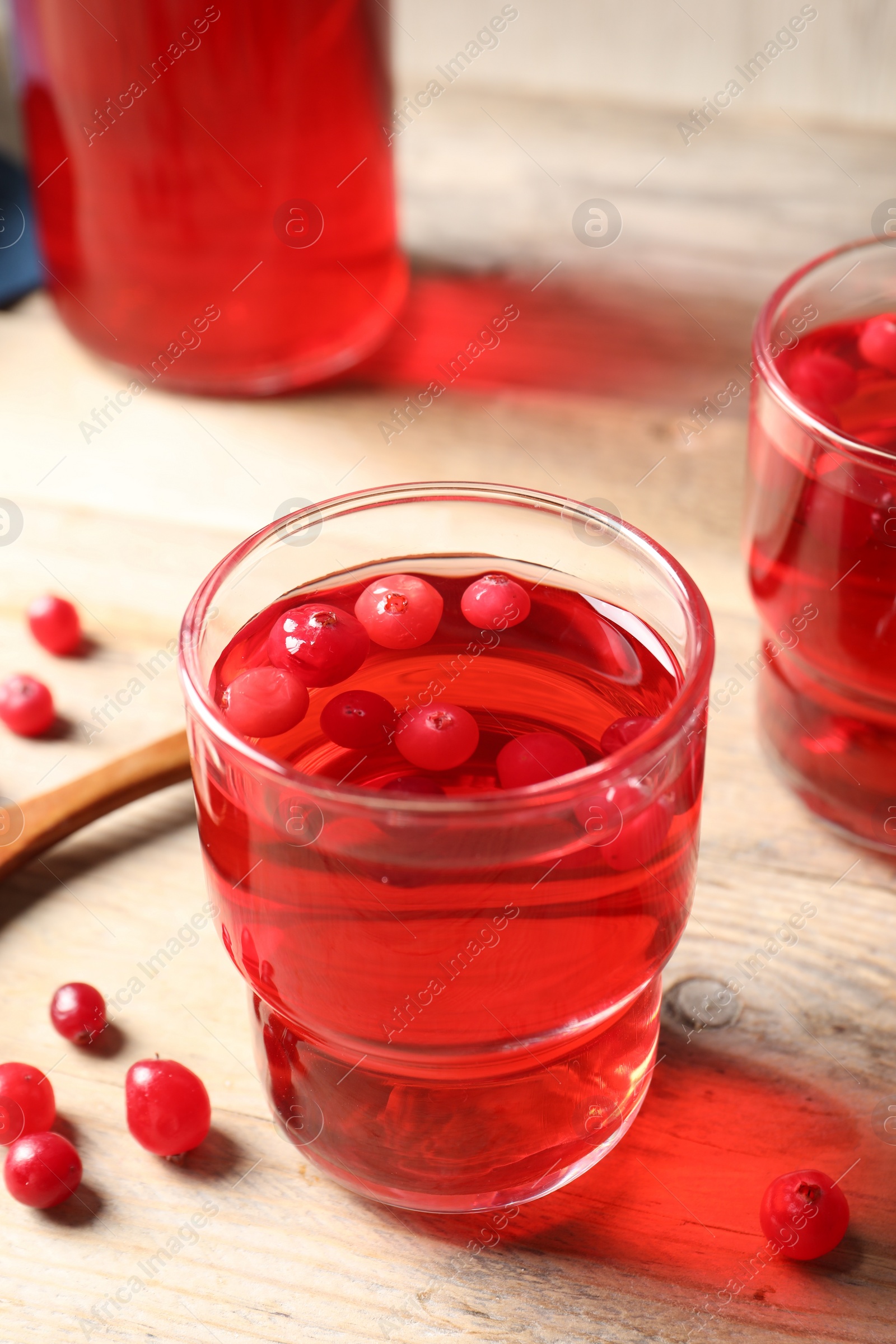 Photo of Tasty cranberry juice in glasses and fresh berries on wooden table, closeup