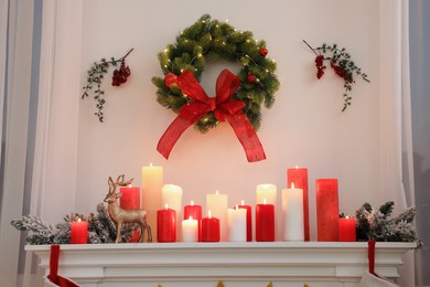 Photo of Beautiful Christmas wreath on wall over decorated fireplace