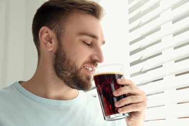 Handsome man with cold kvass indoors. Traditional Russian summer drink