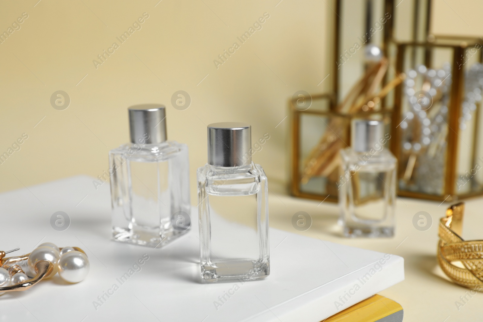 Photo of Bottle of perfumes and stylish earrings on magazines