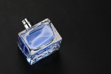 Photo of Blue men's perfume in bottle on black background, above view. Space for text