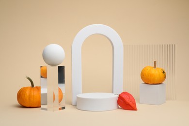 Photo of Autumn presentation for product. Geometric figures, pumpkins and physalis on beige background