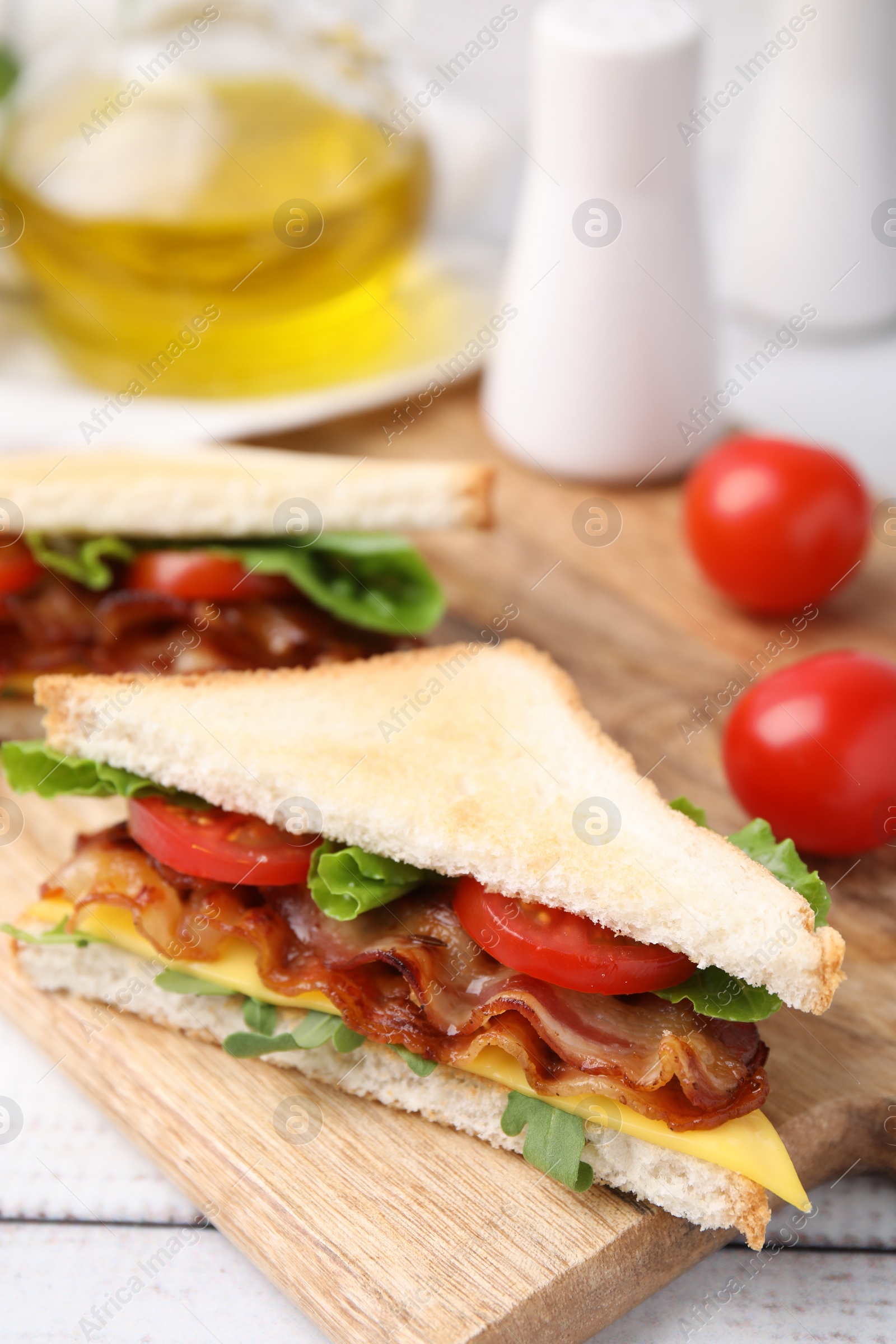 Photo of Delicious sandwich with fried bacon on wooden rustic table, closeup