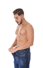 Photo of Fit man in oversized jeans on white background. Weight loss