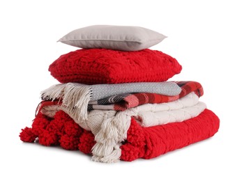 Stack of pillows and folded warm plaids on white background