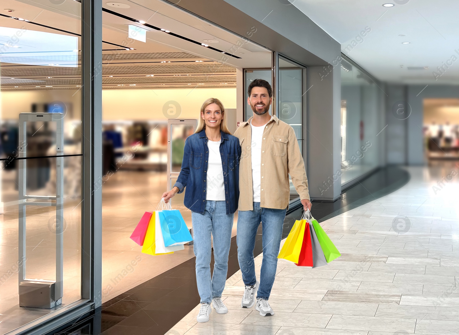 Image of Happy couple with shopping bags walking in mall