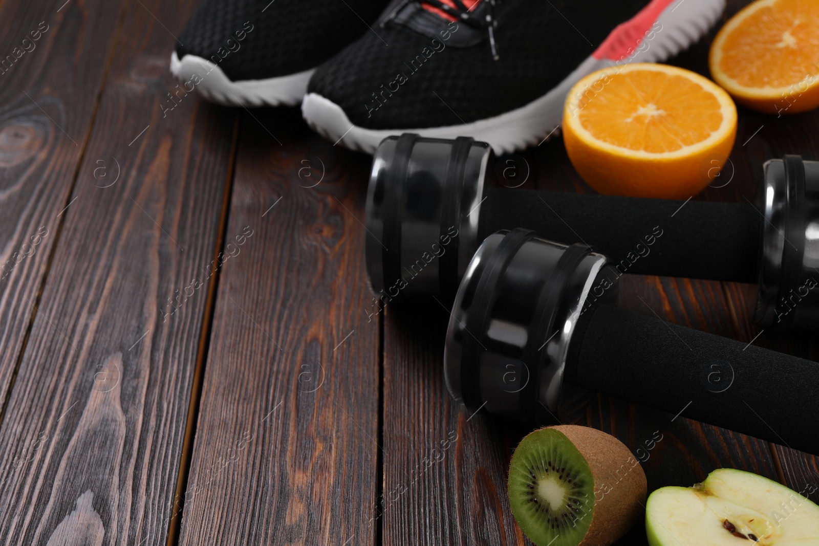 Photo of Weight loss concept. Sneakers, dumbbells and products on wooden table, space for text