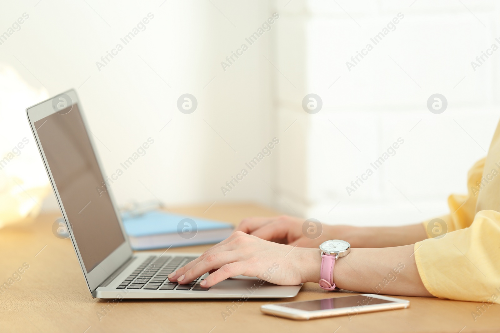 Photo of Young woman using laptop at table indoors, closeup