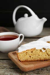 Piece of homemade yogurt cake with cream and cup of tea on wooden table