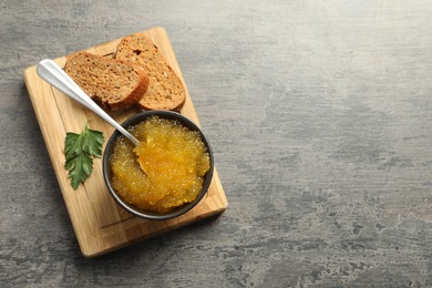 Photo of Fresh pike caviar in bowl, parsley and bread on grey table, top view. Space for text