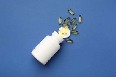 Bottle of vitamin capsules on blue background, top view