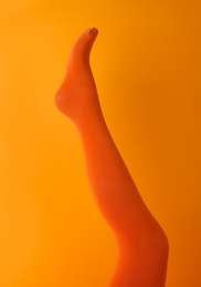 Photo of Leg mannequin in orange tights on color background